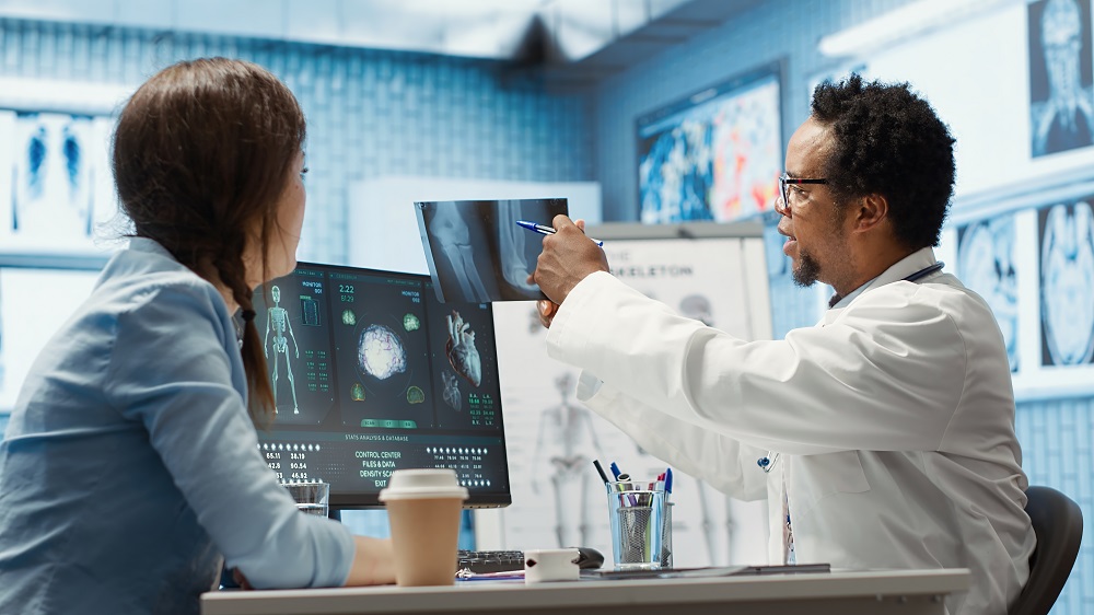 General practitioner examining x ray scan test results with patient